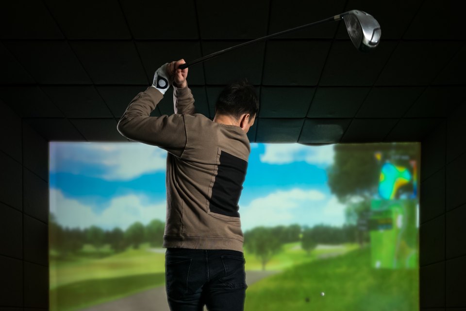 Mies pelaa golf-simulaattorilla